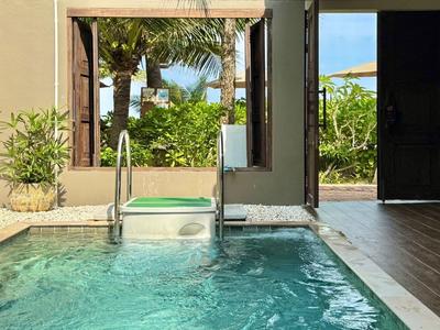 Piscina privata con scalini, circondata da piante e accesso a un giardino