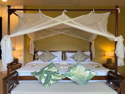 Camera accogliente con letto a baldacchino, zanzariera e cuscini decorativi.