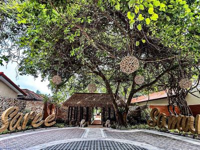 Großer Baum mit Sitzbereich und dekorativen Holzbuchstaben im Außenbereich eines Hotels.