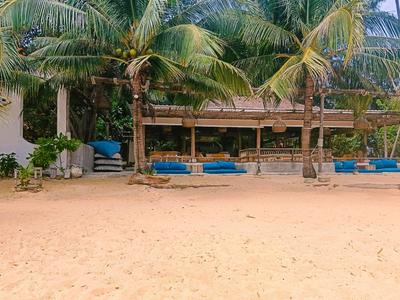Strandbar met palmbomen, blauwe kussens en zand op de voorgrond