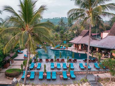 Großer Pool mit blauen Liegestühlen und Palmen in tropischer Hotelanlage.