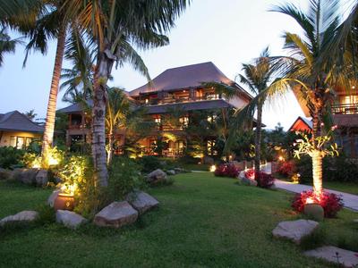 Beleuchtetes tropisches Resort mit Palmen und gepflegtem Rasen in der Abenddämmerung