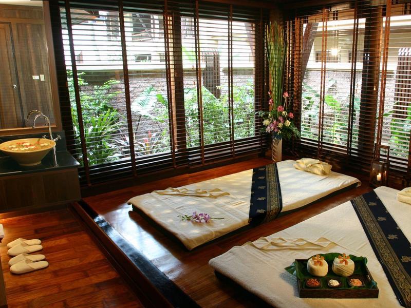 Habitación con dos camas bajas, persianas de madera y flores decorativas