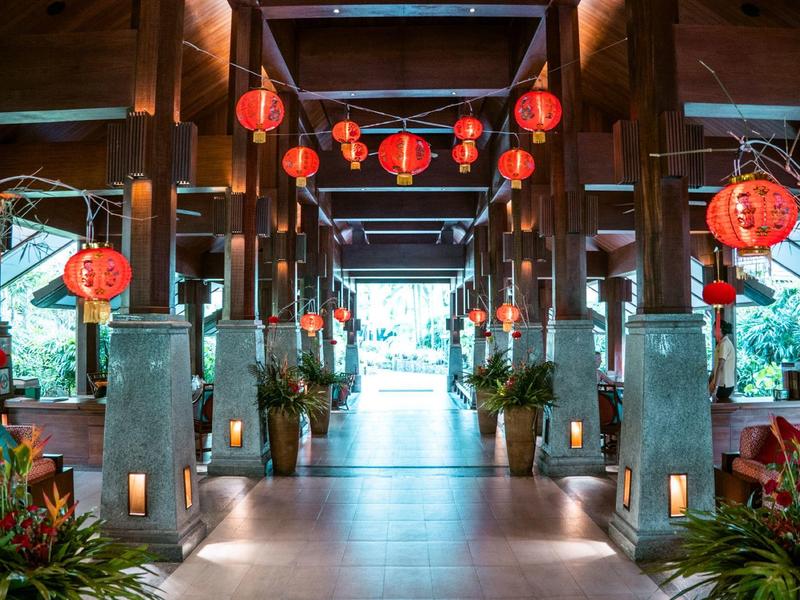 Área de entrada con faroles rojos y decoración tropical en un hotel.