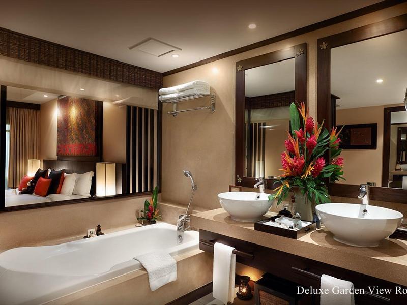 Habitación de hotel moderna con bañera, dos lavabos y flores decorativas.