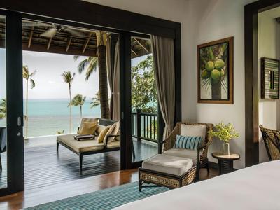 Uitzicht van binnen naar een gezellig hotelbalkon met zitplaatsen en uitzicht op zee.