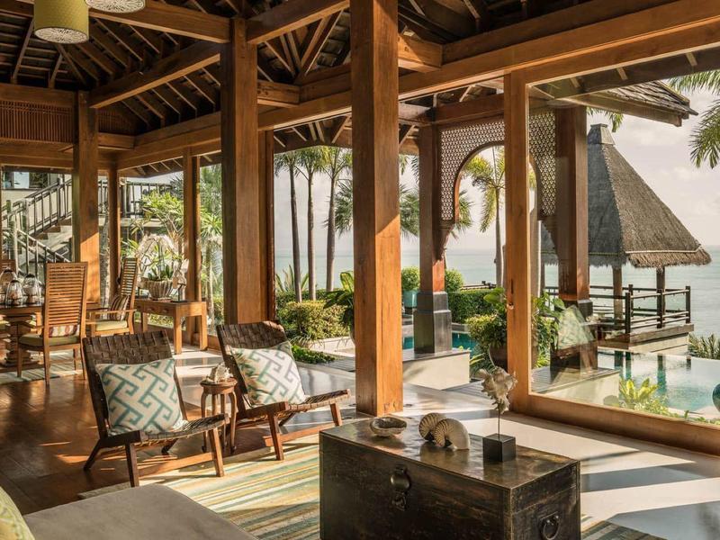 Licht ingerichte kamer met balkon en uitzicht op tropisch strand en palmbomen.