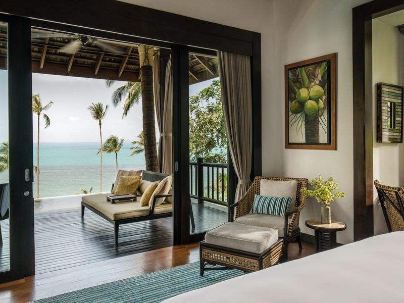 Uitzicht van binnen naar een gezellig hotelbalkon met zitplaatsen en uitzicht op zee.