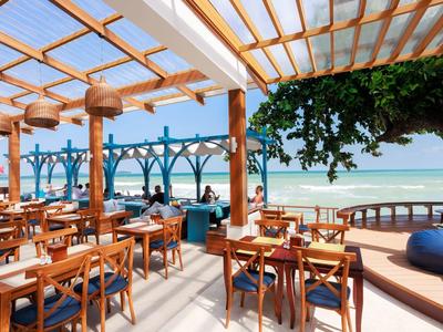 Offener Speisebereich mit Holzstühlen und Blick auf das Meer unter einem Glasdach.