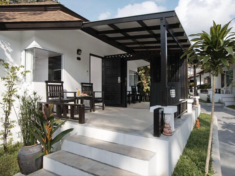 Widok na białe patio z krzesłami i stolikami przed hotelem lub domem wakacyjnym.