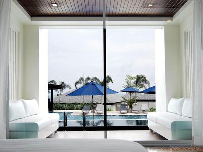 Habitación de hotel con balcón abierto, vista a la piscina y palmeras a la luz del día