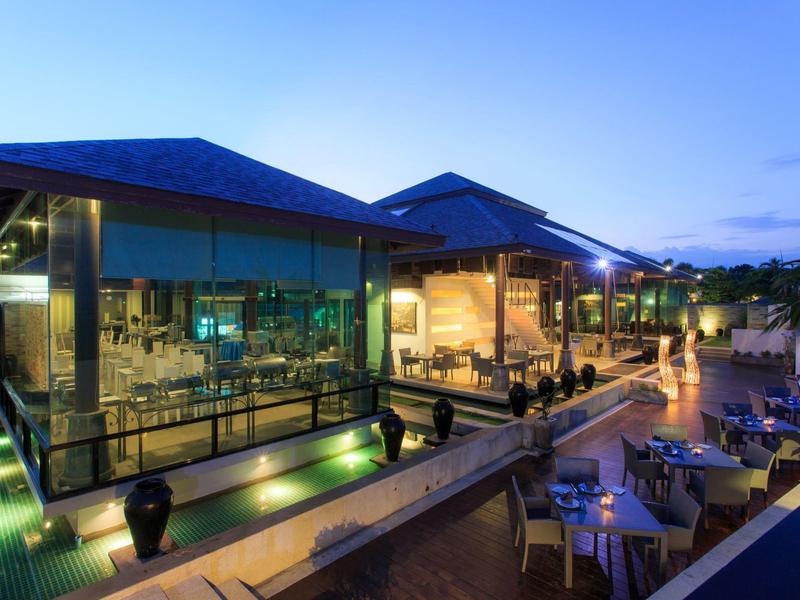 Terraza moderna del hotel con piscina iluminada y zona de asientos al anochecer