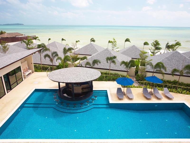 Piscina de lujo con bar y tumbonas con vistas al océano y palmeras.