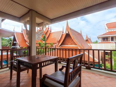 Balcon couvert avec table et chaises en bois, vue sur des toits thaïlandais traditionnels