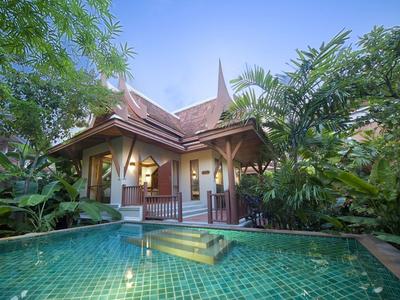 Villa de luxe avec toit traditionnel et piscine privée entourée d'une végétation tropicale.