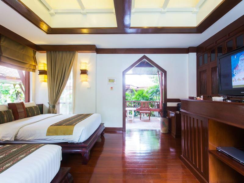 Chambre d'hôtel avec deux lits, sol en bois, télévision et accès à un balcon avec vue sur le jardin.