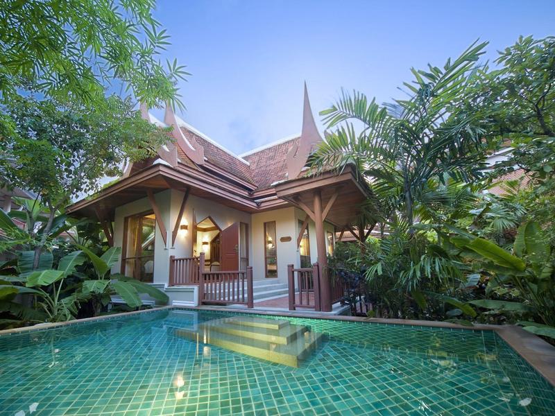 Villa de luxe avec toit traditionnel et piscine privée entourée d'une végétation tropicale.