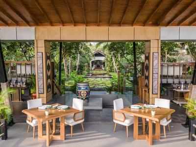 Area pranzo aperta con tavoli in legno e vista su giardino e padiglione