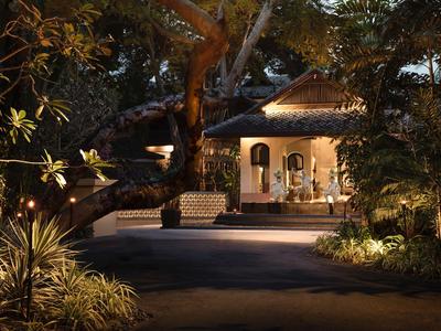 Accogliente ristorante all'aperto in un giardino tropicale di notte con luce calda.