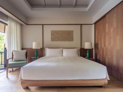 Camera d'hotel luminosa e moderna con un grande letto, due comodini e accesso al balcone.