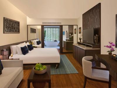 Camera d'hotel moderna con letto grande, area salotto e scrivania, decorata caldamente.