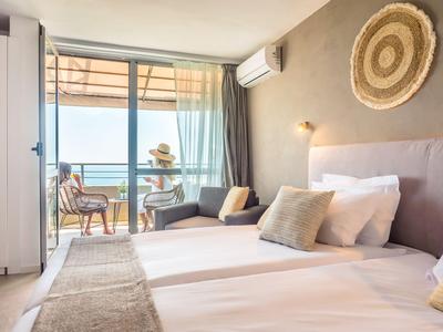 Modernes Schlafzimmer mit Doppelbett, Balkon und Meerblick in einem Hotel.