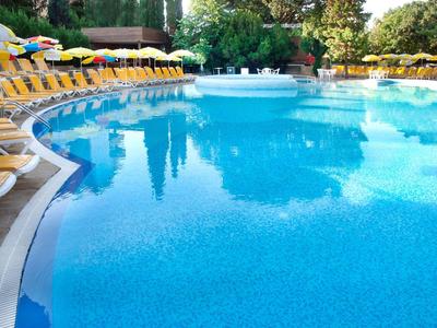 Groot blauw zwembad met veel gele ligstoelen bij zonnig weer.