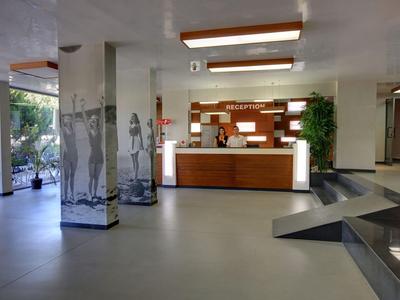 Moderne Hotelrezeption mit Holzfront, großzügigem Empfangsbereich und Pflanzen.