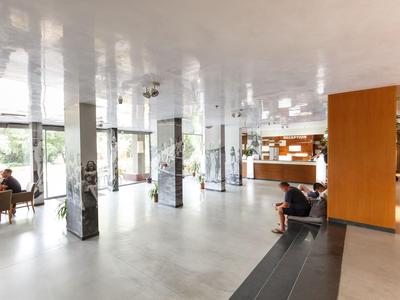 Moderner Hotel-Lobbybereich mit Sitzgelegenheiten, Rezeption und großen Fenstern.