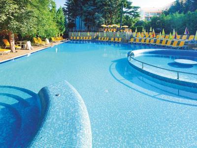 Großer blauer Pool mit Sonnenliegen und Sonnenschirmen im Außenbereich.