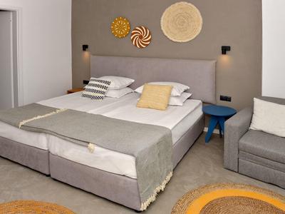 Modern ingerichte hotelkamer met tweepersoonsbed, grijze accenten en gezellige zithoek.