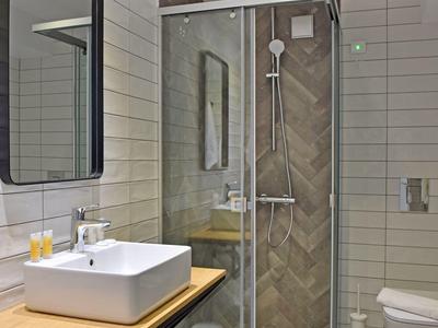 Moderne badkamer met hoekdouche, wasbak op houten blad en wandspiegel.