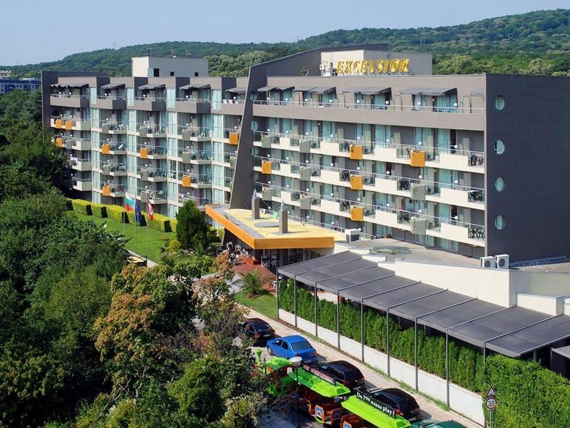 Meerdere verdiepingen tellend hotelgebouw met balkons voor beboste heuvels.