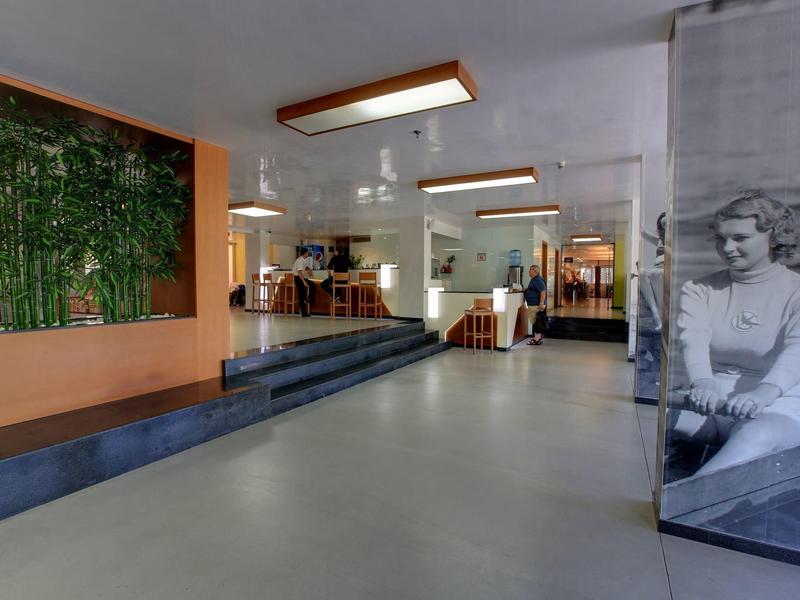 Moderne hotel lobby met zitplaatsen, trappen en decoratieve plantenwanden.