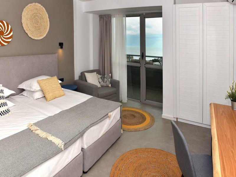 Moderne hotelkamer met tweepersoonsbed, balkon en nautische decoratie.