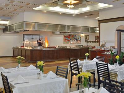 Heller Speisesaal mit gedeckten Tischen und Buffetbereich im Hintergrund.