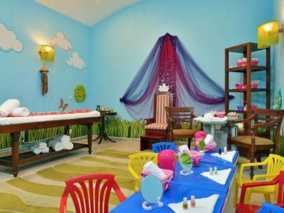 Bunt dekorierter Raum mit Massagetisch und blau gedecktem Kindertisch für Hotelgäste.