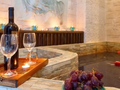 Romantischer Whirlpoolbereich mit Weinflasche, Gläsern und Kerzenlicht in entspannter Atmosphäre.