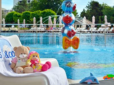 Poolbereich mit Liegestuhl, Kissen, Stofftieren und Wasserattraktion im Hotelumfeld