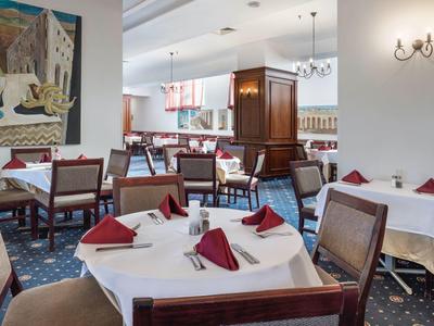 Eleganter Speisesaal mit weißen Tischdecken und rot gefalteten Servietten in einem Hotel.