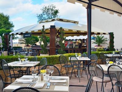 Terrasse eines Außenrestaurants mit gedeckten Tischen und Stühlen unter einem Sonnenschirm und Pavillon