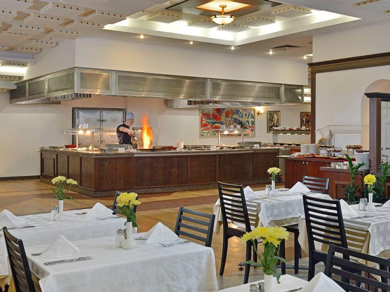 Helles Restaurant mit weiß gedeckten Tischen und offener Küche im Hintergrund.