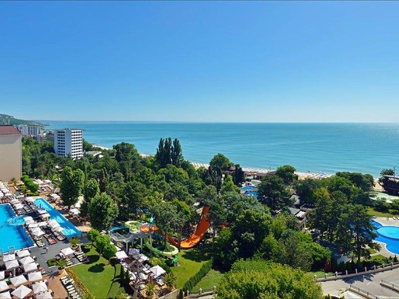 Panoramablick auf ein Hotelresort mit mehreren Pools, grünen Gärten und Meer im Hintergrund