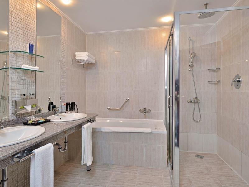 Modernes Badezimmer mit Doppelwaschbecken, Badewanne und separater Dusche mit Glastür.
