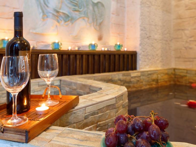 Romantischer Whirlpoolbereich mit Weinflasche, Gläsern und Kerzenlicht in entspannter Atmosphäre.