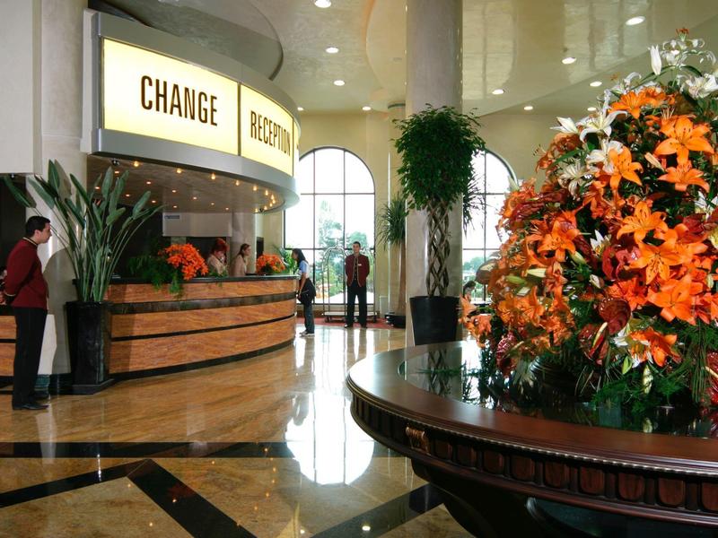 Innenraum einer Wechselstube mit Marmorboden und großer blumiger Pflanzenarrangement im Vordergrund.