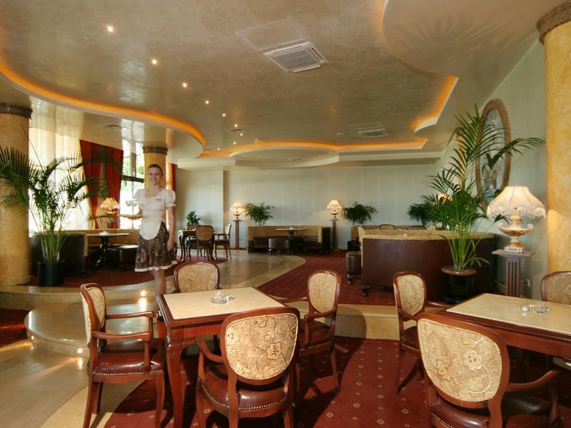 Eleganter Gastraum mit braunen Möbeln, grünen Pflanzen und warmem, gedämpftem Licht.