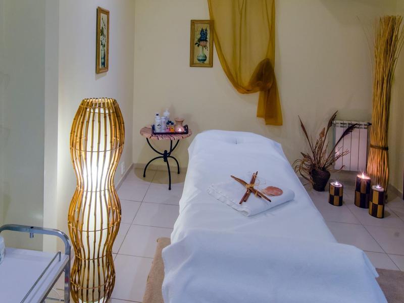 Gemütlicher Raum mit weißen Fliesen, einem dekorativen Stuhl, Kerzen und warmem Licht.