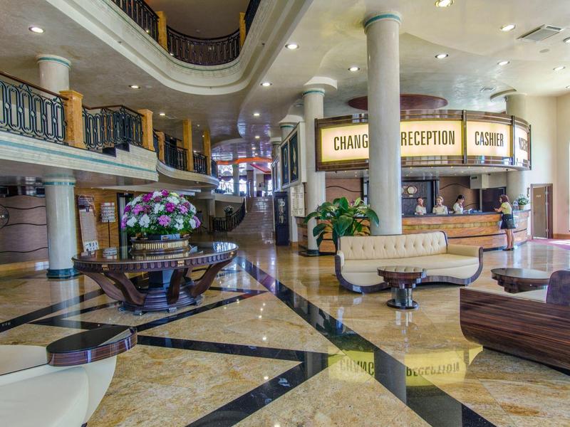 Großer Hotellobby mit Marmorboden, Empfangstresen, Sitzgruppen und Blumenarrangements.