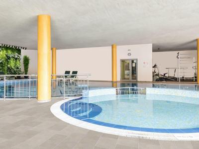 Innenpoolbereich mit runden Becken, gelben Säulen und Blick auf einen Fitnessraum